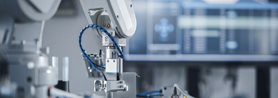 An industrial robot operates on a production line, with cables, wires and automation components visible in close-up.