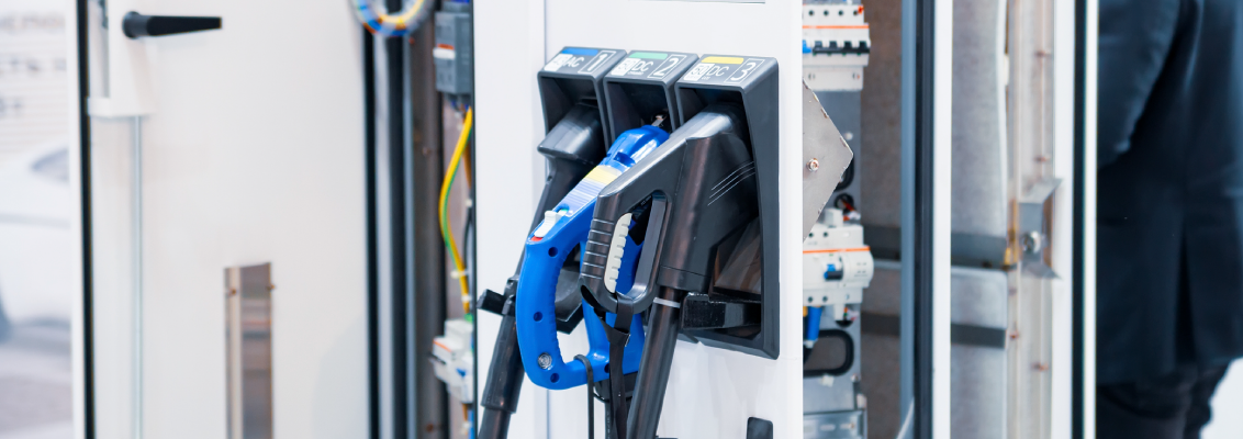 Electric vehicle charging station with open electrical cabinet – cabling and connections in an industrial environment.